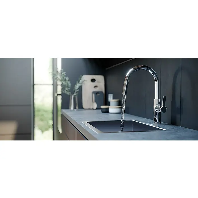 Lenz Spültischarmatur Anela - Chrom, Glänzend, Mit Handbrause - Elegantes Küchendesign mit einem modernen Chromwasserhahn, der Wasser in ein dunkles Spülbecken fließen lässt, umgeben von stilvollen Dekorationen.