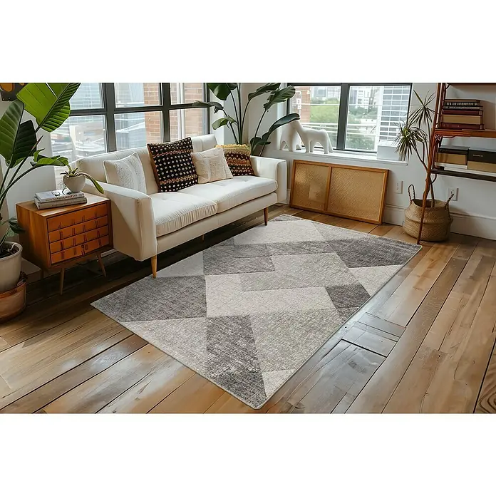 Kurzflorteppich Trendy CarvingSilber, 150 x 80 cm, 100 % Polypropylen - Ein grauer Teppich mit geometrischem Muster liegt unter einem weißen Sofa auf einem Holzboden.