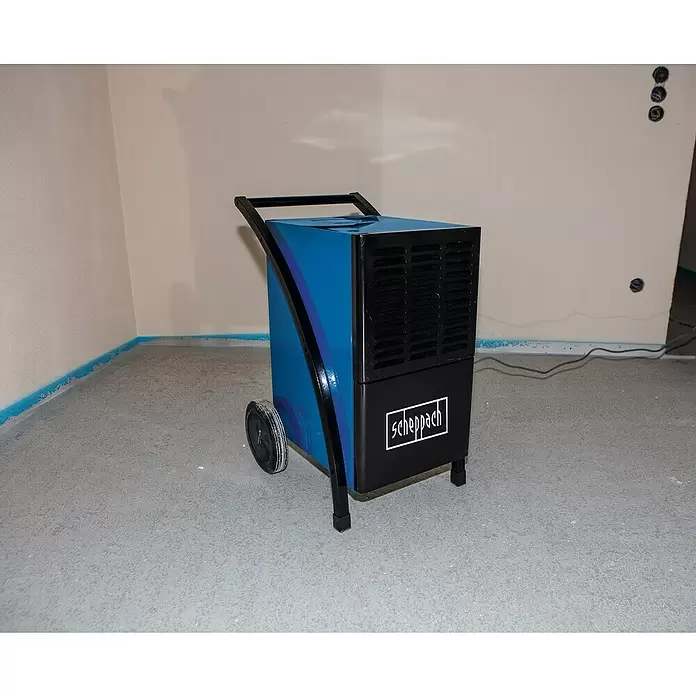 Scheppach Bautrockner BTR6500 - Entfeuchtungsleistung: 60 l/Tag, Raumgröße: 60 m² - 80 m² - Blauer und schwarzer Industrietrockner mit Rollen und Griff, in einem Raum im Bau.