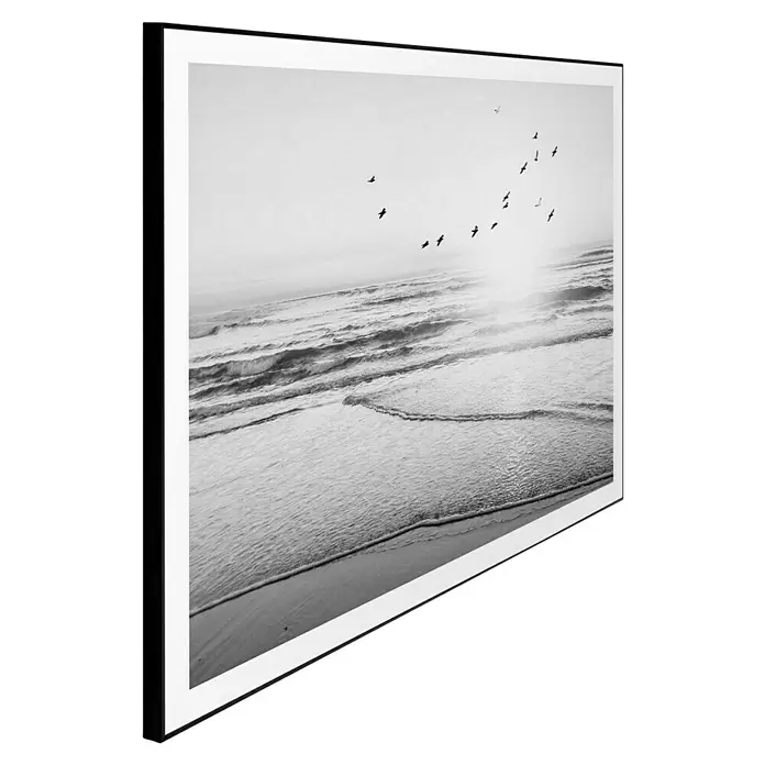 Reinders Bild Slim Frame Black - Beach Serenity, B x H: 70 x 50 cm - Schwarz gerahmter Schwarz-Weiß-Druck einer Strandszene mit Wellen und Vögeln am Himmel, schräg dargestellt.