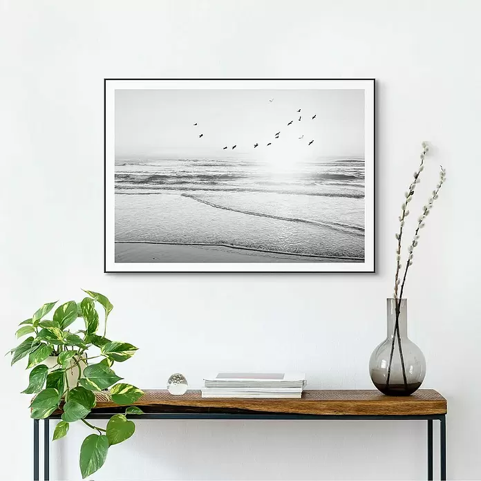 Reinders Bild Slim Frame Black - Beach Serenity, B x H: 70 x 50 cm - Schwarz gerahmtes Foto einer Schwarz-Weiß-Strandszene mit Vögeln und Sonne, über einem Konsolentisch.