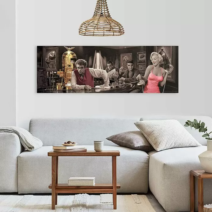Reinders Decopanel - Chris Consani - Java Dreams, An x Al: 156 x 52 cm - Lámina panorámica de James Dean, Elvis y Marilyn Monroe en un bar, sepia con acentos de color, colgada sobre un sofá gris.