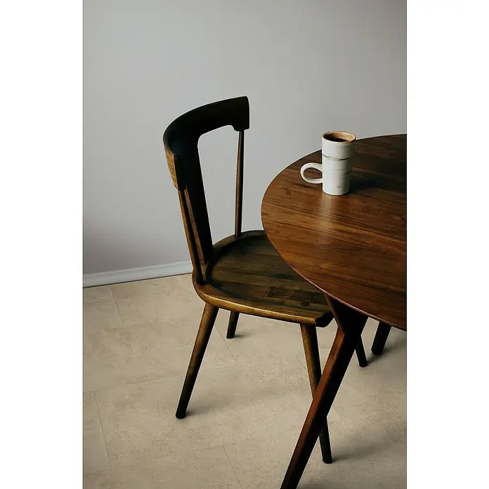 Gerflor Vinylbodenmuster Rigid Acoustic Oliva Beige - 250 x 399 x 5,4 mm, Oliva Beige - Ansicht eines Holztisches mit einer Tasse Kaffee und einem Stuhl. Die natürliche Holzmaserung betont die Tischplatte und verleiht der Szene Wärme.