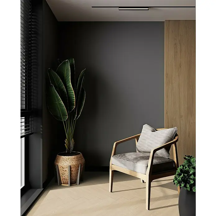 Gerflor Vinylboden Rigid Acoustic - Tulum Beige, Fischgrät, 750 x 125 x 6 mm - Die stilvolle Leseecke mit einem bequemen Sessel aus hellem Holz und einem großen Zimmerpflanze bietet eine entspannende Atmosphäre.