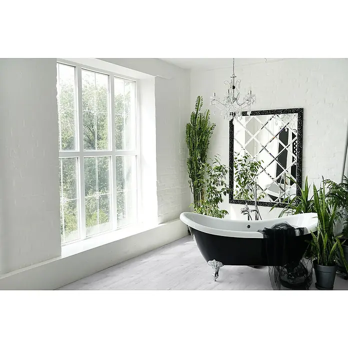 Gerflor Vinylbodenmuster Rigid Acoustic Sola Snow - 250 x 229 x 5,4 mm, Sola Snow - Ein elegantes Badezimmer in Weiß mit einer freistehenden Badewanne in Schwarz, umgeben von Pflanzen und einem dekorativen Spiegel.