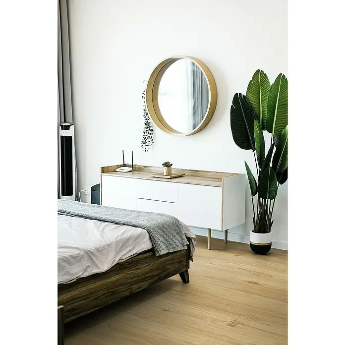 Gerflor Vinylbodenmuster Rigid Acoustic Savanna - 250 x 229 x 5,4 mm, Savanna - Schlafzimmerszene mit einem Bett, einem runden Spiegel und einer Kommode. Der Raum ist hell und modern eingerichtet.
