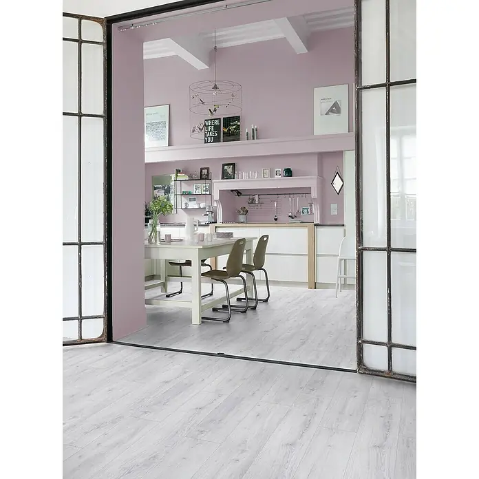 Gerflor Vinylbodenmuster Rigid Acoustic Sola Snow - 250 x 229 x 5,4 mm, Sola Snow - Blick in ein modernes Esszimmer mit weißem Holztisch, Stühlen und grauem Holzboden durch eine Glasschiebetür.