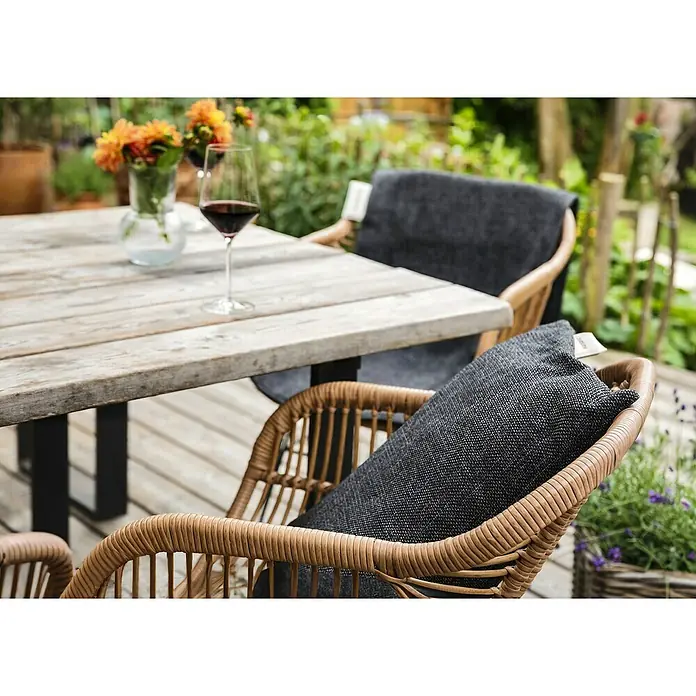 Montandor Heizkissen - 60 x 15 cm, Dunkelgrau - Einladende Gartenszene mit Rattan-Stühlen und bequemen Kissen, die zum Verweilen bei einem Glas Wein im Freien einlädt.