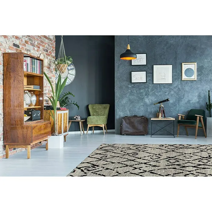 Kayoom Flachgewebeteppich River 110 - Grau/Schwarz, 170 x 120 cm, 70 % Baumwolle, 30 % Polyester - Ein beiger Teppich mit einem schwarzen geometrischen Muster liegt in einem gemütlichen Wohnzimmer mit vintage Möbeln.