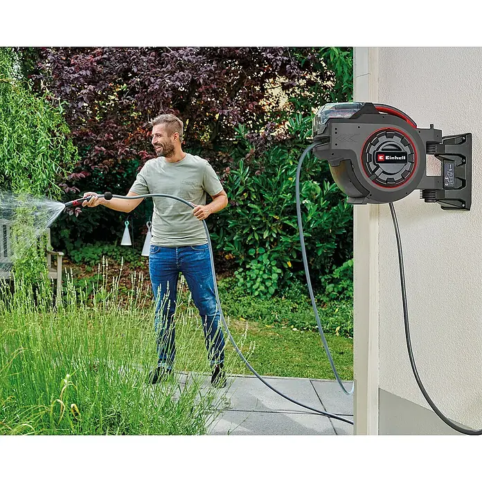 Einhell Power X-Change 18V Akku-Schlauchtrommel GE-HR 18/30-1 - 18 V, Ohne Akku - Ein Mann benutzt eine Einhell Schlauchbox zur Gartenbewässerung. Das Gerät ist an einer Wand montiert und ermöglicht eine einfache Handhabung des Gartenschlauchs.