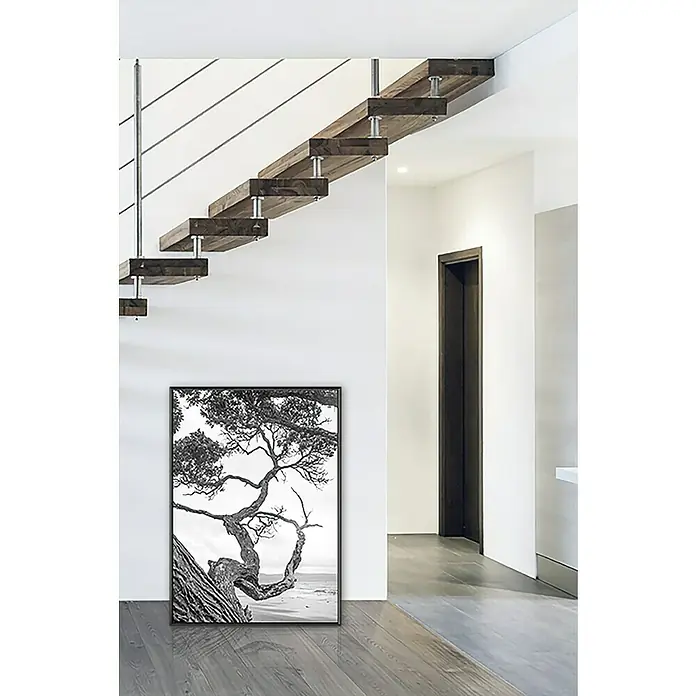 Nielsen Alurahmen Classic - DIN A2 / 42 x 59,4 cm, Contrastgrau - Moderne Inneneinrichtung mit freitragender Holztreppe, Edelstahlgeländer und einem gerahmten Schwarz-Weiß-Baumfoto an der Wand.