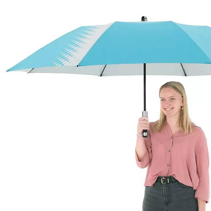 Doppler Expert Strandschirm Manual Muli - Blau/Silber, Durchmesser Bespannung: 160 cm - Junge Frau hält geöffneten blauen Regenschirm mit weißem Punktmuster.