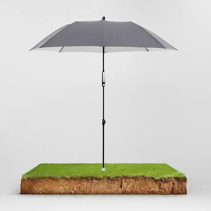 Doppler Expert Strandschirm Manual Muli - Anthrazit, Durchmesser Bespannung: 160 cm - Grauer Sonnenschirm mit schwarzem Stock, steht in einem quadratischen Stück Gras und Erde.