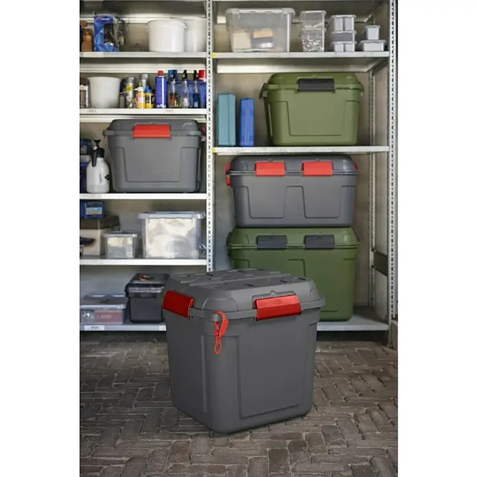Sunware Aufbewahrungsbox Q-Line wasserdicht - L x B x H: 60,1 x 53,1 x 54,5 cm, Kunststoff, Anthrazit - Ein grauer Aufbewahrungsbehälter mit roten Verschlüssen vor einem Regal voller weiterer Behälter.