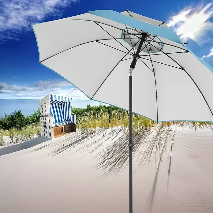Doppler Strandschirm Windprofi Neo - Hellblau, Durchmesser Bespannung: 200 cm - Weißer Sonnenschirm mit blauen Akzenten offen am Sandstrand, spendet Schatten nahe einem Strandkorb.