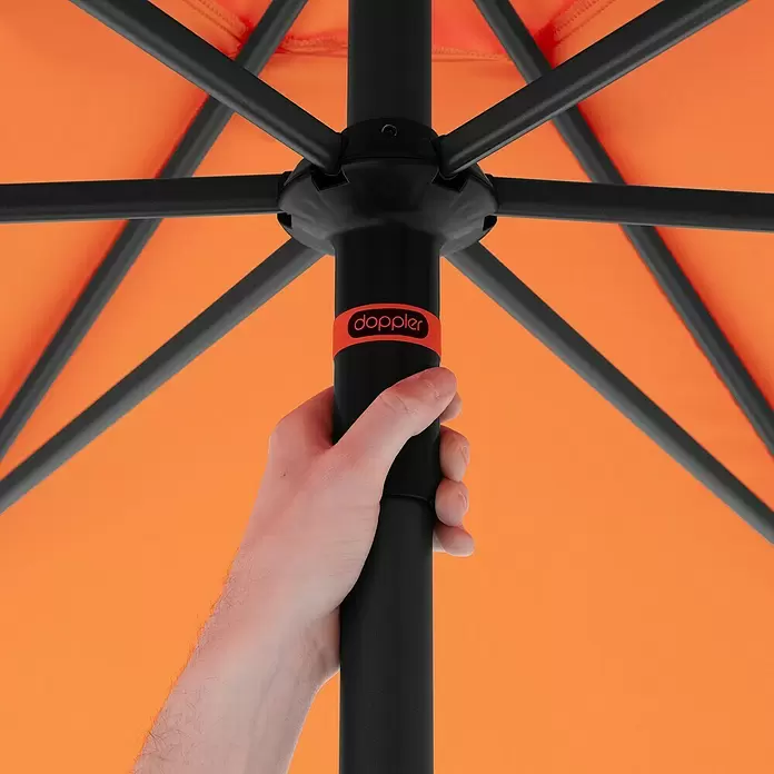 Doppler Marktschirm myZone Push Up - Orange, Durchmesser Bespannung: 300 cm - Hand hält schwarzen Stock eines geöffneten orangefarbenen Doppler-Schirms von unten. Schwarzes Gestell trägt das leuchtend orange Verdeck.