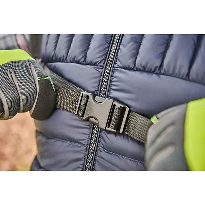 Ryobi Max Power Akku-Laubbläser RY36BPXB-0 Whisper - Ohne Akku, Blasgeschwindigkeit: 277 km/h, Blasleistung: 20,2 m³/min - Nahaufnahme einer Person, die eine schwarze Schnalle an einem dunkelblauen gesteppten Rucksack befestigt, mit grauen und neongelben Handschuhen.
