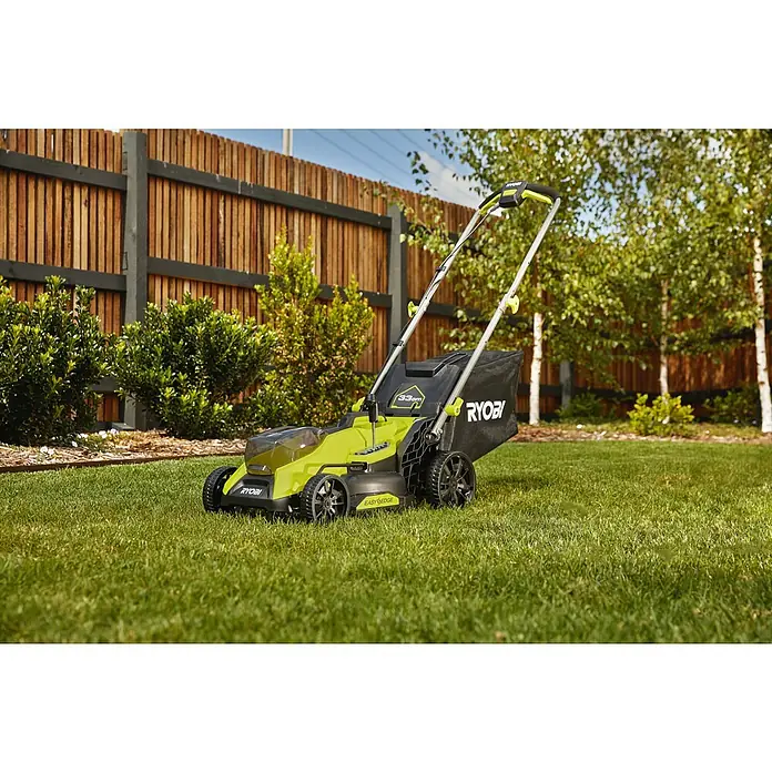 Ryobi ONE+HP Akku-Rasenmäher RY18LMX33A-0 - 18 V, Ohne Akku, Schnittbreite: 33 cm - Ein grüner Ryobi Rasenmäher steht auf einem gepflegten Rasen vor einem Holzzaun, bereit für den nächsten Einsatz.
