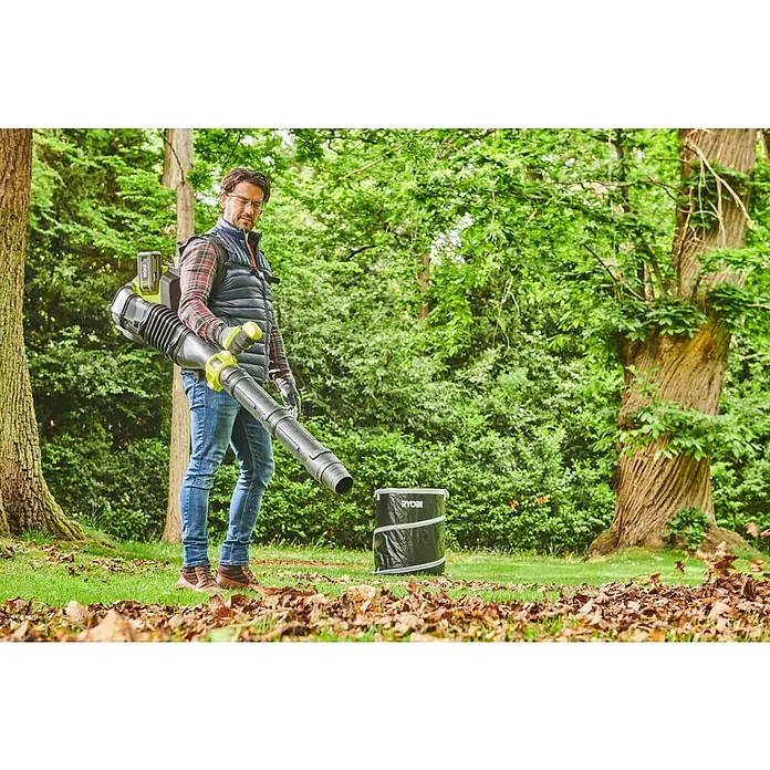 Ryobi Max Power Akku-Laubbläser RY36BPXB-0 Whisper - Ohne Akku, Blasgeschwindigkeit: 277 km/h, Blasleistung: 20,2 m³/min - Ein Mann benutzt einen Ryobi Laubbläser im Garten, um gefallenes Laub zu entfernen, mit einem Laubsack in der Nähe für die Sammlung.