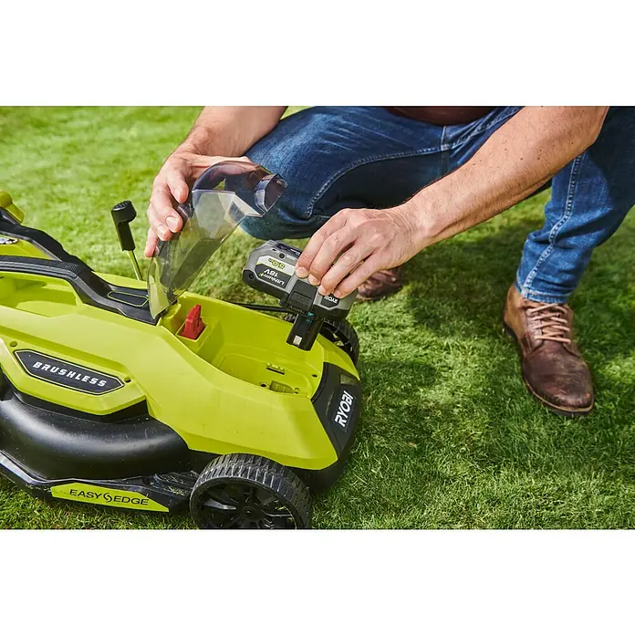 Ryobi ONE+HP Akku-Rasenmäher RY18LMX33A-0 - 18 V, Ohne Akku, Schnittbreite: 33 cm - Ein Mann setzt einen 18V Lithium+ Akku in einen gelb-schwarzen Ryobi Rasenmäher ein. Der Rasenmäher ist bürstenlos und hat einen Easy Edge.