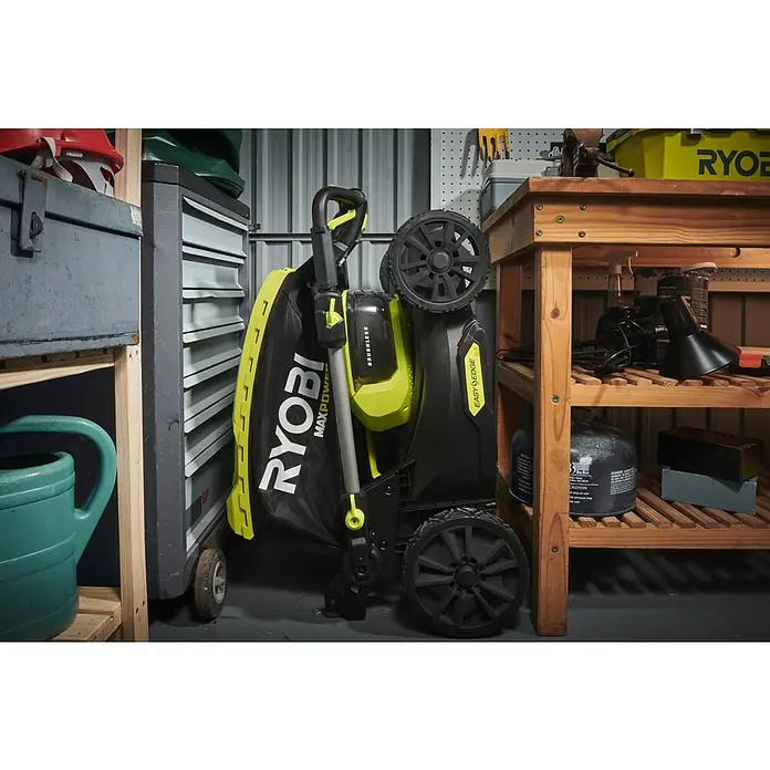 Ryobi Max Power Akku-Rasenmäher RY36LMX46A-150 - 36 V, 1 Akku, 5 Ah, Schnittbreite: 46 cm - Nahaufnahme eines Ryobi Max Power Laubbläsers mit Beutelaufsatz, der in einer Garage oder Werkstatt steht.