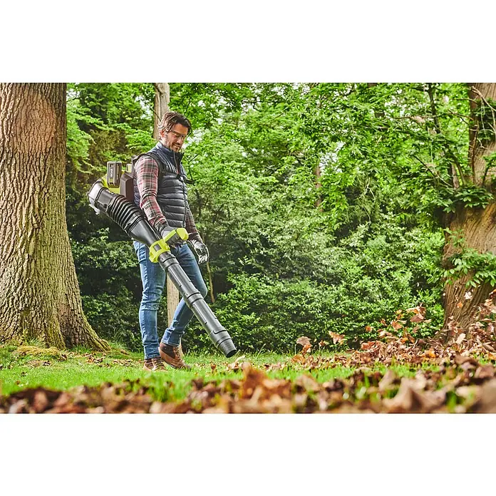 Ryobi Max Power Akku-Laubbläser RY36BPXB-0 Whisper - Ohne Akku, Blasgeschwindigkeit: 277 km/h, Blasleistung: 20,2 m³/min - Ein Mann bedient einen Laubbläser im Freien. Der Laubbläser ist schwarz mit grünen Akzenten.