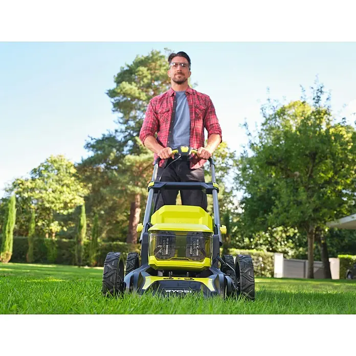 Ryobi ONE+ Akku-Rasenmäher RY18LMX46A-0 - 18 V, Ohne Akku, 5 Ah, Schnittbreite: 46 cm - Ein Mann mäht Rasen mit einem gelb-schwarzen Ryobi Akku-Rasenmäher im Garten, umgeben von Bäumen, an einem sonnigen Tag.