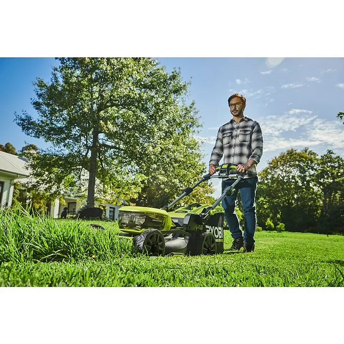 Ryobi Max Power Akku-Rasenmäher RY36LMX46A-150 - 36 V, 1 Akku, 5 Ah, Schnittbreite: 46 cm - Ein Mann mäht Rasen mit einem grünen Ryobi Akku-Rasenmäher im Garten, umgeben von Bäumen und einem Haus.