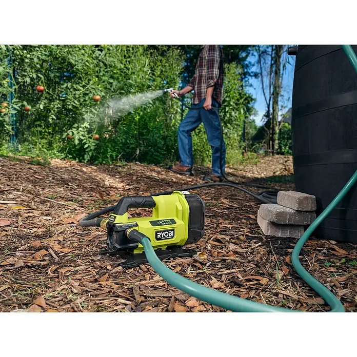 Ryobi ONE+ Akku-Gartenpumpe RY18TPXA - 18 V, Li-Ionen, Ohne Akku, Max. Fördermenge: 2.270 l/h - Nahaufnahme einer Ryobi-Wasserpumpe im Garten mit Person im Hintergrund, die Pflanzen bewässert.