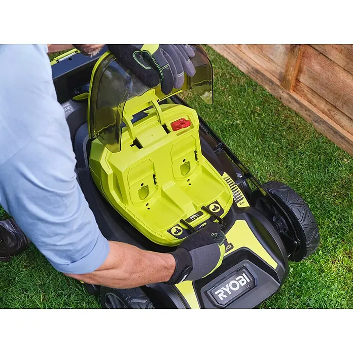 Ryobi ONE+ Akku-Rasenmäher RY18LMX46A-0 - 18 V, Ohne Akku, 5 Ah, Schnittbreite: 46 cm - Nahaufnahme eines Mannes, der einen gelben Ryobi-Rasenmäher bedient, wobei der Fokus auf den Details des Geräts liegt.