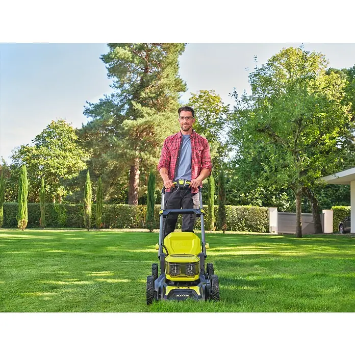 Ryobi ONE+ Akku-Rasenmäher RY18LMX46A-0 - 18 V, Ohne Akku, 5 Ah, Schnittbreite: 46 cm - Ein Mann, der einen gelben Ryobi Rasenmäher auf einer grünen Rasenfläche bedient, mit Bäumen und einem Haus im Hintergrund.