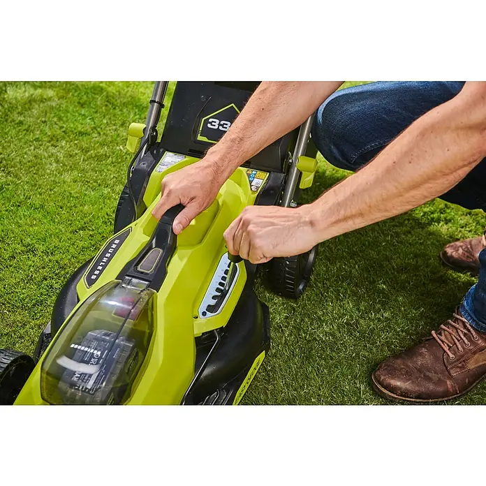 Ryobi ONE+HP Akku-Rasenmäher RY18LMX33A-0 - 18 V, Ohne Akku, Schnittbreite: 33 cm - Eine Nahaufnahme eines Mannes, der die Schnitthöhe eines gelb-schwarzen Rasenmähers einstellt, auf Rasen.