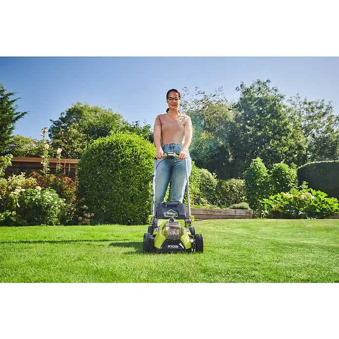 Ryobi ONE+HP Akku-Rasenmäher RY18LMX33A-0 - 18 V, Ohne Akku, Schnittbreite: 33 cm - Eine Frau mäht den Rasen mit einem grünen RYOBI Rasenmäher. Der Rasenmäher ist das Hauptaugenmerk des Bildes.