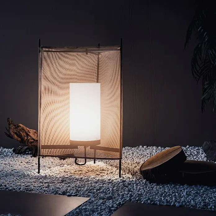 Tween Light LED-Dekoleuchte Rossa - 40 W, Taupe, Ø x H: 46 x 65 cm - Elegante Innenraumaufnahme einer modernen Tischleuchte mit einem Schirm aus Mesh, die auf weißen Kieselsteinen steht und ein warmes Licht ausstrahlt.