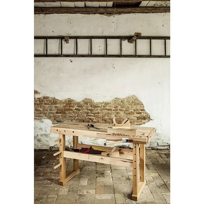 Banco de trabajo - L x An: 1.400 x 500 mm, Altura de trabajo: 830 mm, Carga soportada: 400 kg, Marrón - Un banco de madera con herramientas frente a una pared rústica. Ideal para artesanos y proyectos de bricolaje.