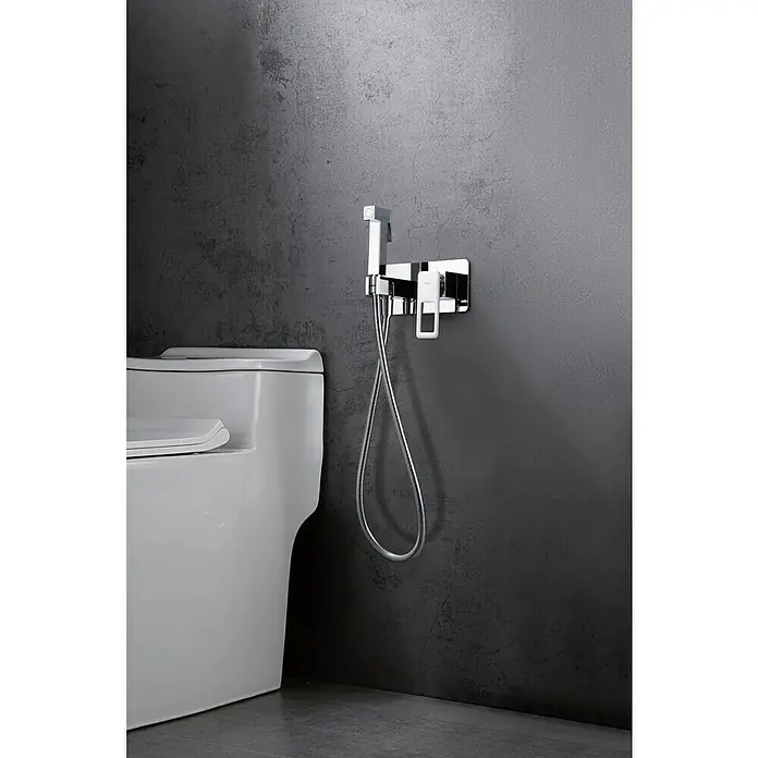 Imex Suecia Ducha higiénica inodoro - Latón - Primer plano de un conjunto de rociador de bidé montado en una pared del baño, junto a un inodoro.