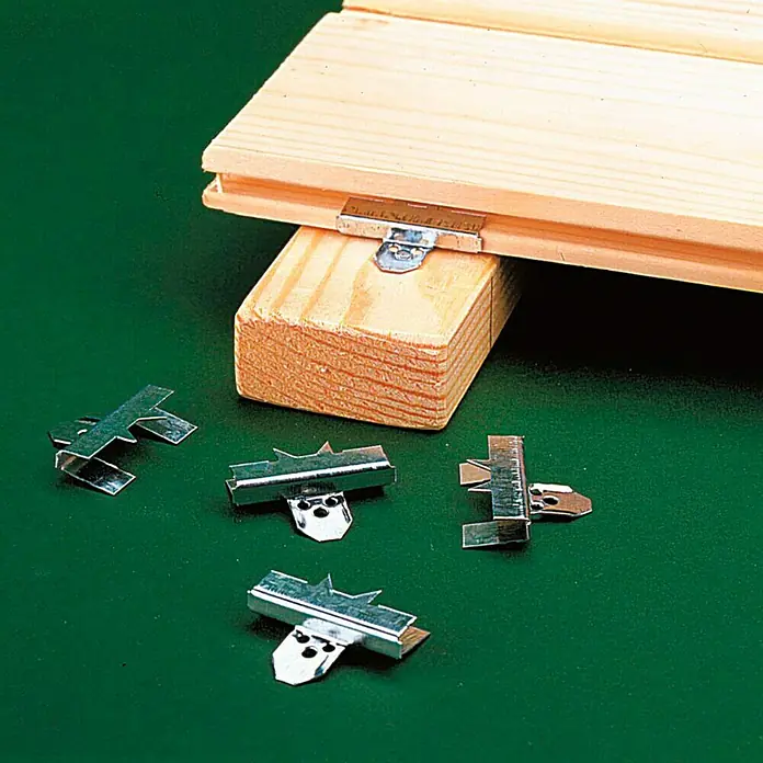 Staba Profilbrettkrallen C 4 - Stärke Nutwange: 4 mm, 250 Stk. - Nahaufnahme von Holzterrassenclips zur Befestigung von Dielen, die auf einer grünen Oberfläche präsentiert werden.