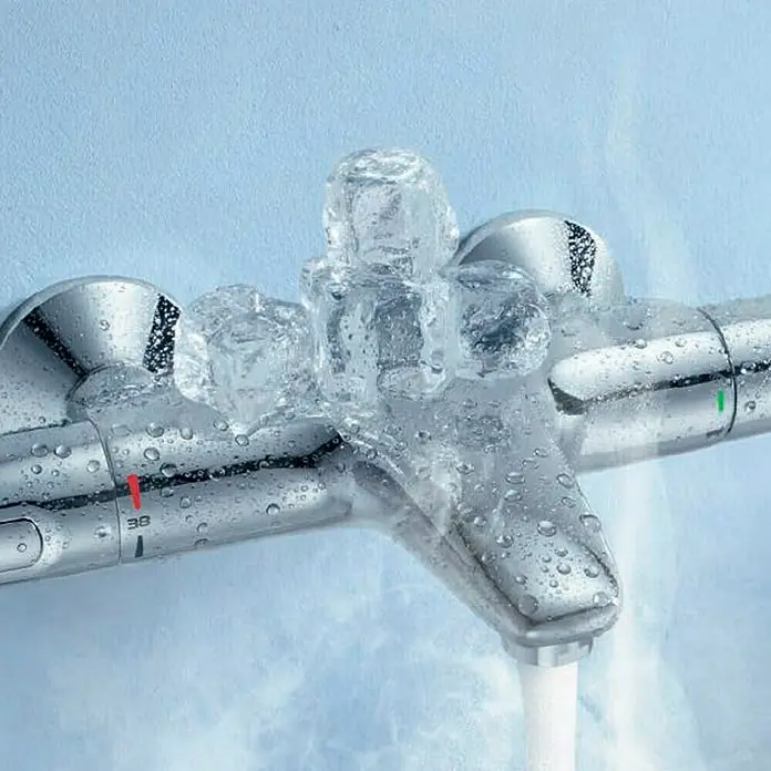 Grohe Grohtherm 1000 New Wannenthermostat - Chrom - Nahaufnahme einer glänzenden Armatur mit Wassertropfen und Eiswürfeln, die Kälte suggeriert.