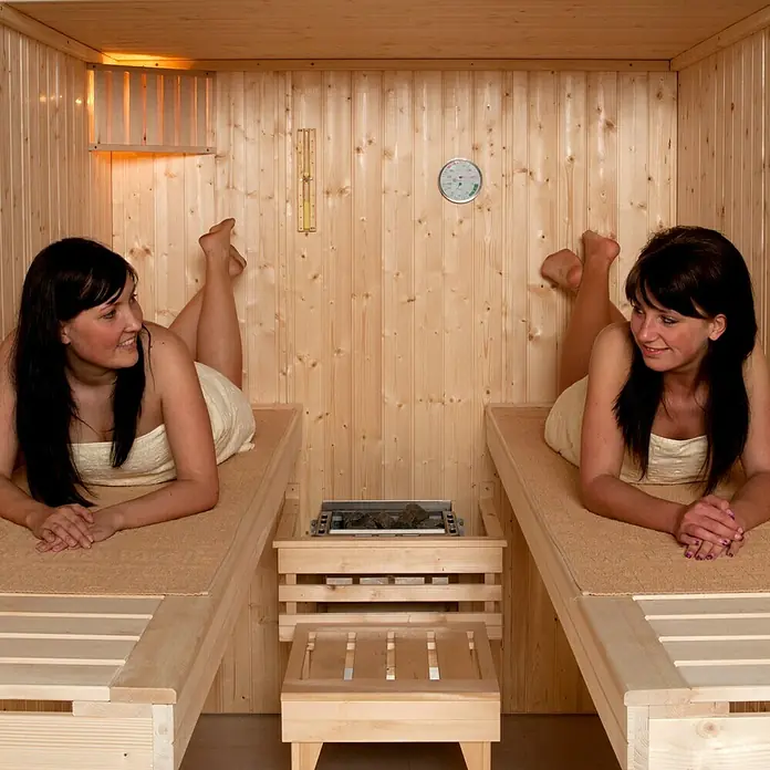 Weka Elementsauna Kaarina 2 - L x B x H: 194 x 177 x 199 cm - Entspannung pur in der Sauna: Zwei Frauen genießen die Wärme und Ruhe auf Holzbänken, ein Thermometer zeigt die ideale Temperatur.