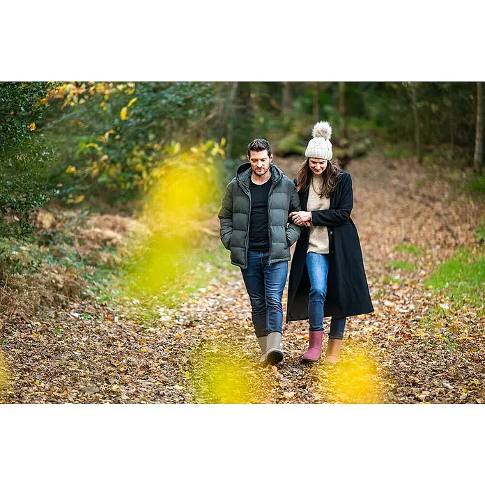 Black Fox Winterstiefel Cheyennetoo - Schuhgröße: 42, Schwarz - Ein Paar spaziert im Herbstwald, die Frau trägt eine modische Mütze. Die frische Luft belebt die Sinne, während sie die Natur genießen.