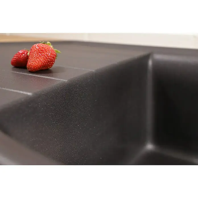 Respekta Einbauspüle Arlington - 110,5 x 52 cm, Schwarz - Nahaufnahme einer schwarzen Küchenspüle mit zwei roten Erdbeeren auf der Ablage, die das moderne Design und die Funktionalität hervorhebt.