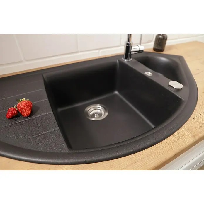 Respekta Einbauspüle Arlington - 110,5 x 52 cm, Schwarz - Nahaufnahme einer modernen schwarzen Küchenspüle mit Abtropffläche und zwei Erdbeeren darauf, die auf einer hellen Holzplatte steht.