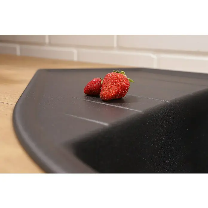 Respekta Einbauspüle Arlington - 110,5 x 52 cm, Schwarz - Nahaufnahme von zwei Erdbeeren, die auf einer modernen, schwarzen Spüle in einer Küche liegen. Perfekt für Küchendekorations- oder Lebensmittelbilder.