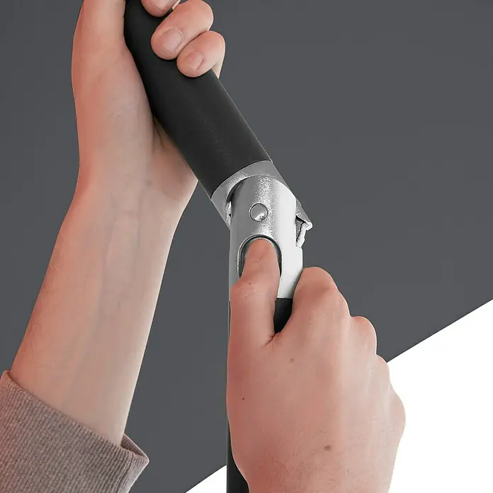 Doppler Marktschirm rund myZone Push Up - Anthrazit, Durchmesser Bespannung: 300 cm - Nahaufnahme einer Hand, die eine Taste an einem Sonnenschirmstock drückt, um ihn zu verstellen, vor einem grauen und weißen Hintergrund.