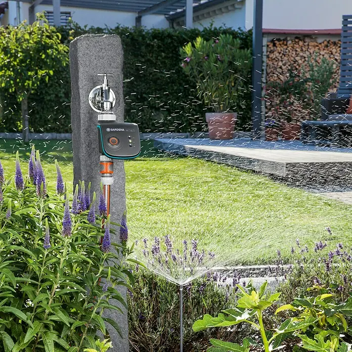 Gardena Smart system Bewässerungsautomat Smart Water Control - Betriebsdruck: 0,5 bar - 12 bar, Bewässerungsdauer: 1 min - 10 h - Gardena Bewässerungssteuerung im Einsatz, montiert an einem Wasserhahn, der einen Rasensprenger speist.