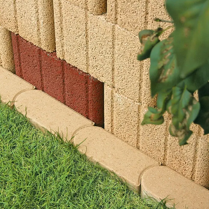 Christoph Mähstein - 22 x 10 x 4,5 cm, Mediterran, Beton - Nahaufnahme einer Gartenmauer aus Betonsteinen mit rotem Akzent und Rasenkante.