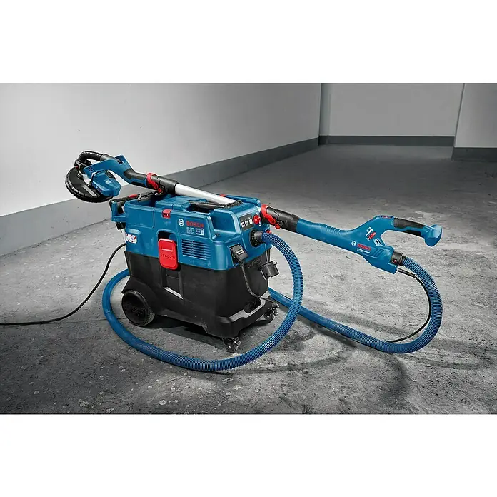 Bosch Professional Elektro-Nass- & Trockensauger GAS 12-40 MA - 1.200 W, 28 l - Bosch Industriesauggerät mit blauer Schleifvorrichtung und Schlauch. Das Gerät steht auf einem grauen Boden vor einer hellen Wand.