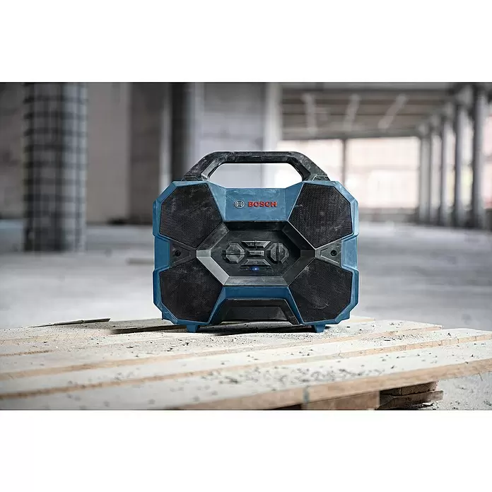 Bosch Professional AMPShare 18V Bluetooth-Lautsprecher GPB 18V-6 C - 18 V, Ohne Akku - Robustes, blau-schwarzes Bosch Baustellenradio mit Lautsprechern und Bedienelementen, auf Holzpalette in Baustellenumgebung.