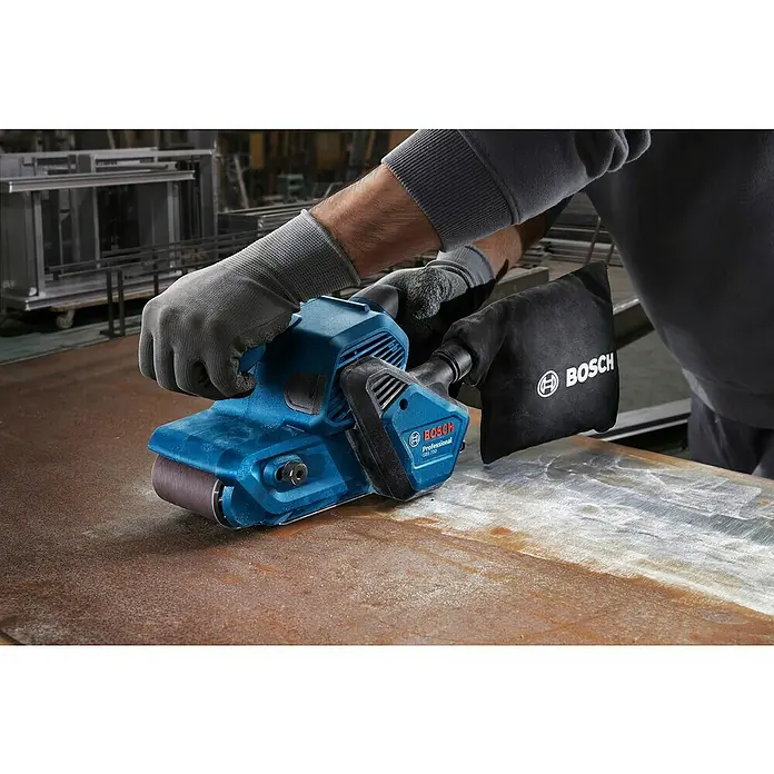 Bosch Professional Elektro-Bandschleifmaschine GBS 750 - 850 W - Der blaue Bosch GBS 75 AE Professional Bandschleifer in Aktion mit Staubbeutel beim Schleifen von Metall.