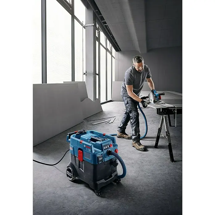 Bosch Professional Elektro-Nass- & Trockensauger GAS 12-40 MA - 1.200 W, 28 l - Baustellenstaubsauger von Bosch im Einsatz, während ein Bauarbeiter eine Platte mit einer Kreissäge zuschneidet.